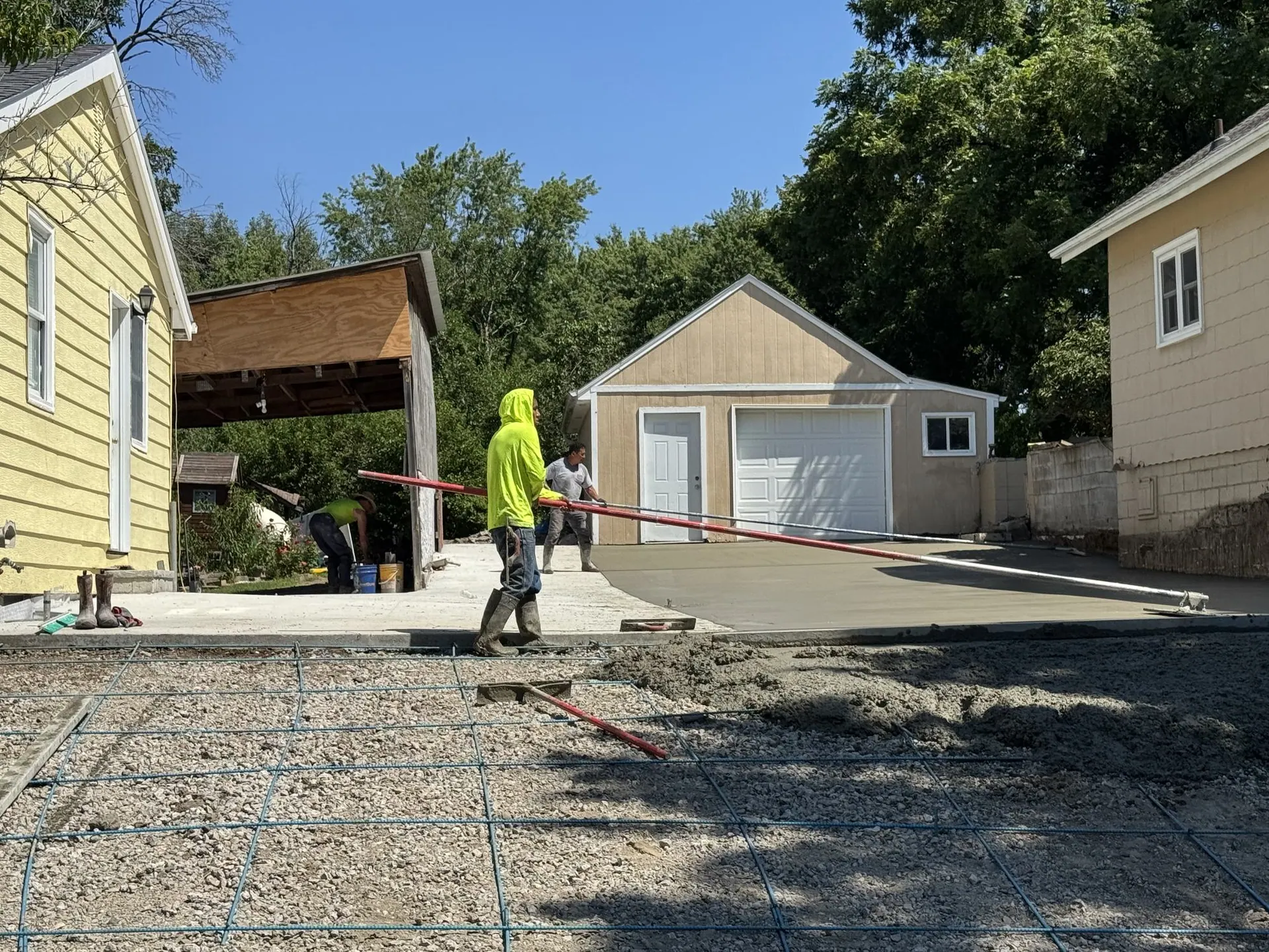 Crew member in a high-visibility shirt placing rebar on a jobsite.